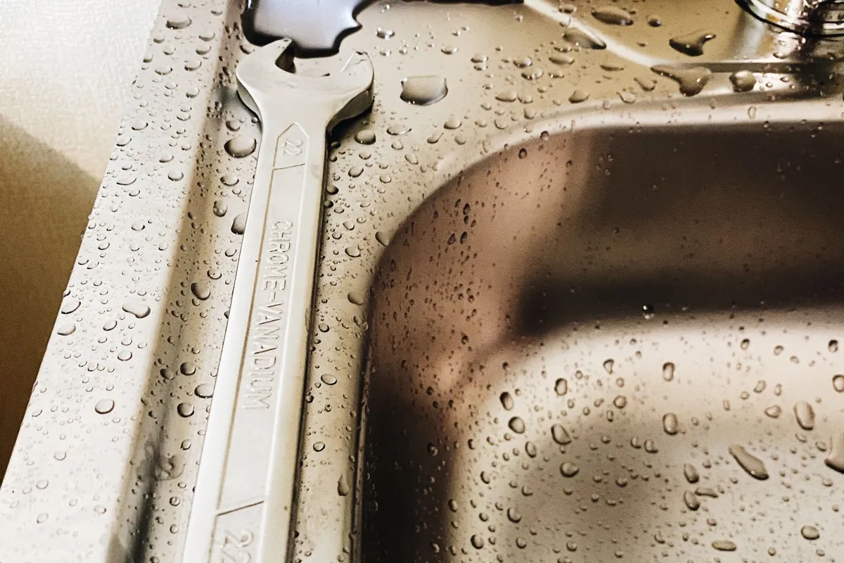 A wrench on a wet sink during a leak repair